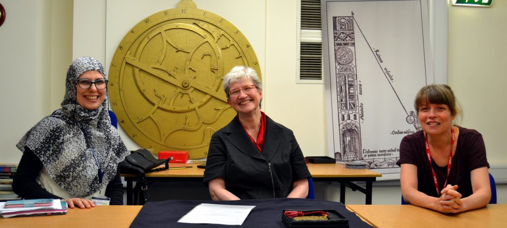 Rana Ibraim, Silke Ackermann and Rachel Harrison sitting at a table. Behind them is a large replica astrolabe that has been attached to the wall. 